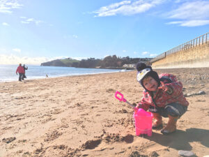 Toddler on Dawlish beach with bucket and spade