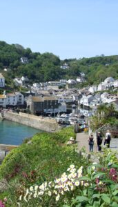 Group of people walking down the South West Coast Path into the fishing village of Polperro