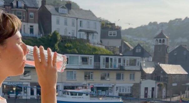 Woman having a drink while looking out across Looe’s harbour